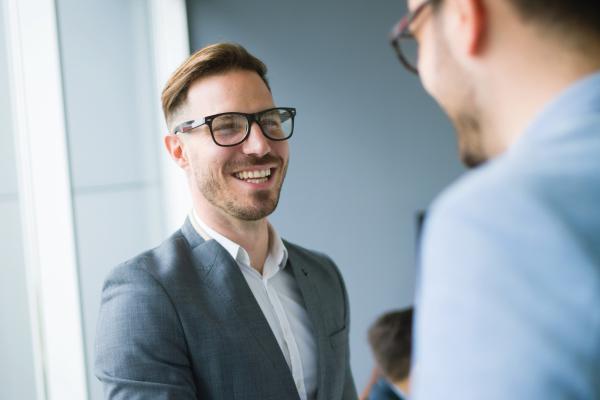 Two men, smartly dressed, talking and smiling