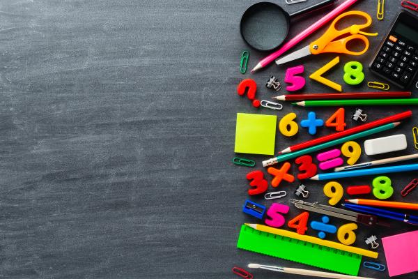 Brightly coloured numbers, calculator and stationery items on a blackboard