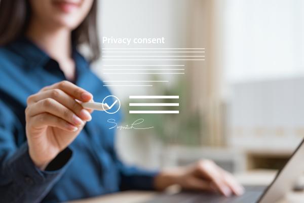 A woman signing a digital privacy consent form on a laptop