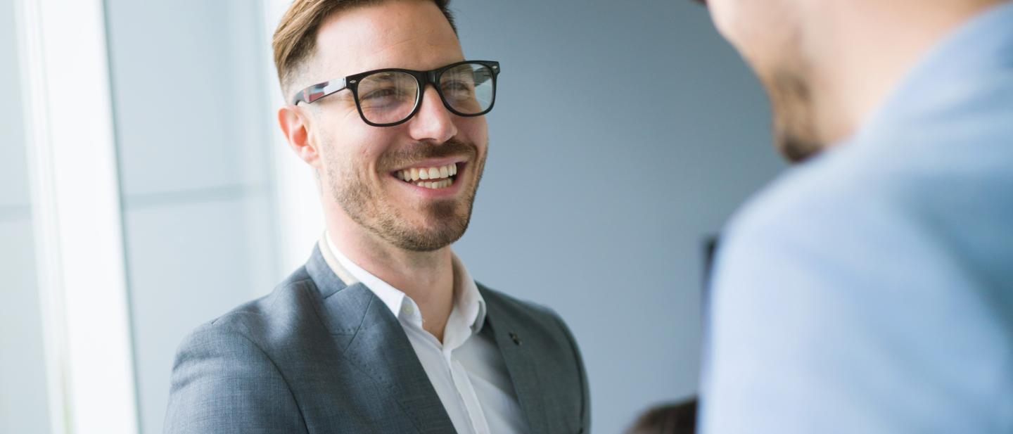 Two men, smartly dressed, talking and smiling