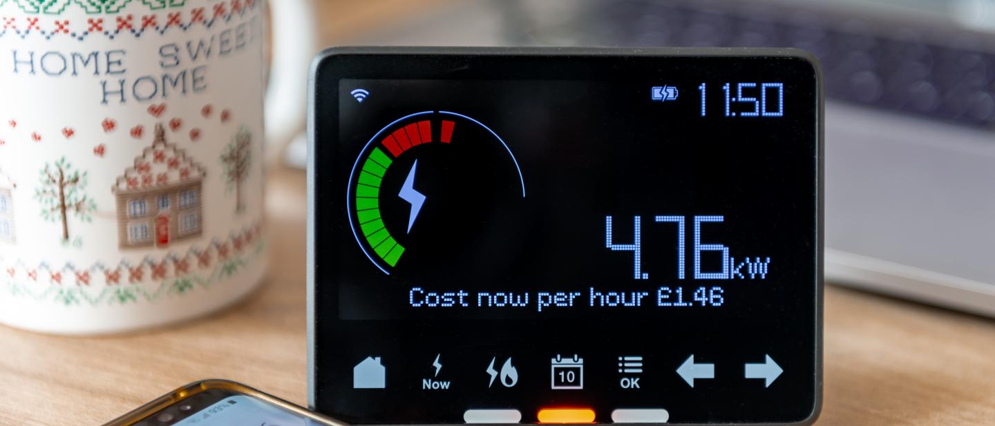 Energy meter, hot drink and a phone on a desk